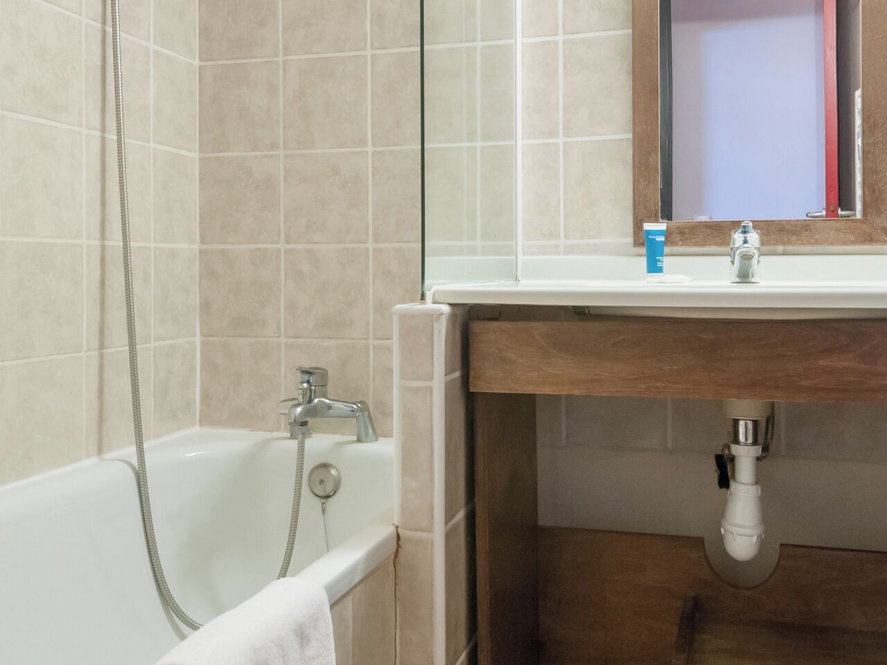 Une salle de bain avec une baignoire, un lavabo et un miroir.