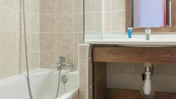 Une salle de bain avec une baignoire, un lavabo et un miroir.