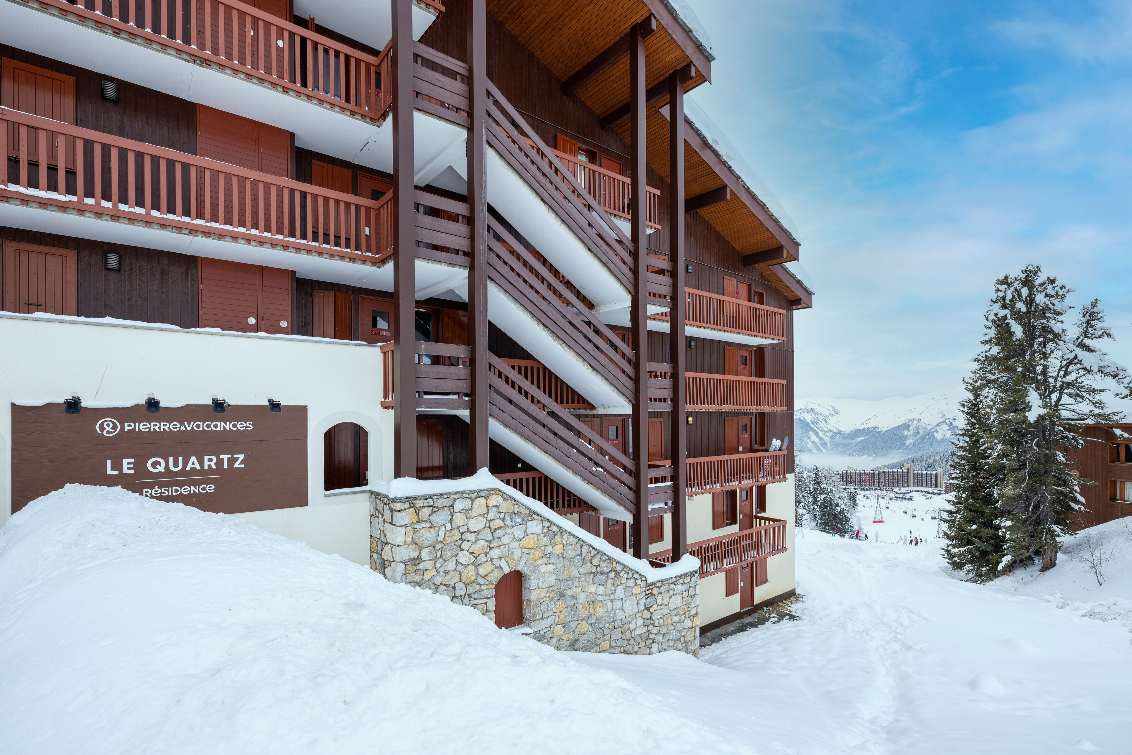 Un hôtel à plusieurs étages, doté d’une façade en pierre, de balcons en bois et d’une enseigne indiquant qu’il s’agit d’une résidence.