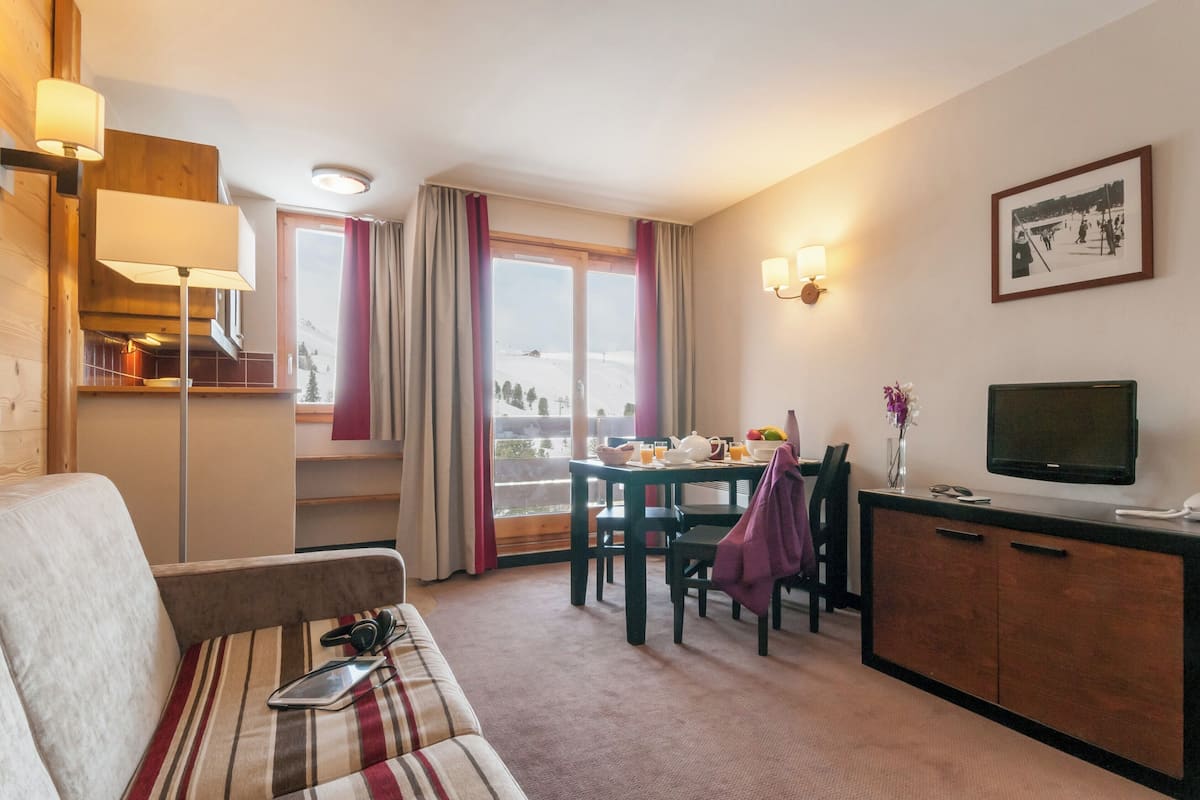 Une chambre d’hôtel confortable, dotée d’un canapé, d’une table à manger et d’un téléviseur.