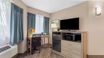 Hotelkamer met bureau, stoel, televisie, magnetron en minibar.