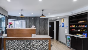 A reception area with a wooden reception desk, a mosaic wall, a clock, and a snack vending machine. - Best Western West Lebanon-Hanover Hotel (West Lebanon)