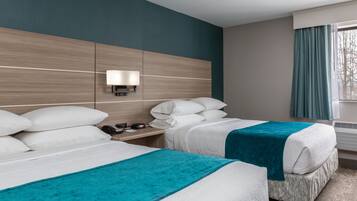 Habitación de hotel con dos camas, una mesita de noche con lámpara y una ventana con cortinas.