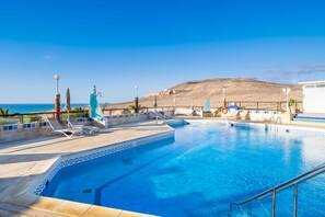 A swimming pool with lounge chairs and a view of the sea. - Hotel Esmeralda Maris by LIVVO (Pajara)