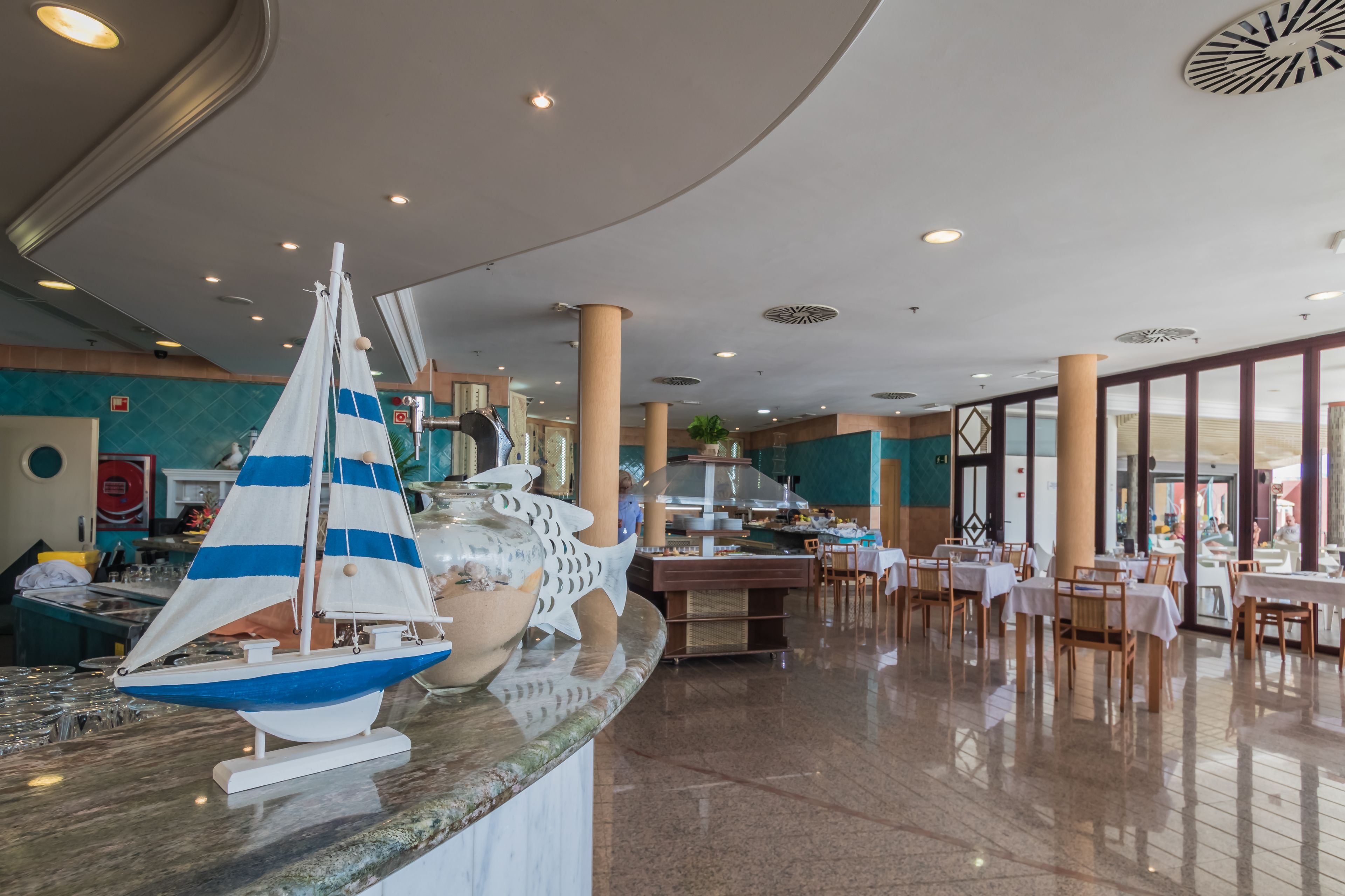 Un hall d’entrée spacieux avec un espace salon central, un bateau de plaisance décoratif et une grande fenêtre offrant une vue sur l’extérieur.