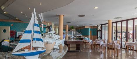 Un hall d’entrée spacieux avec un espace salon central, un bateau de plaisance décoratif et une grande fenêtre offrant une vue sur l’extérieur.