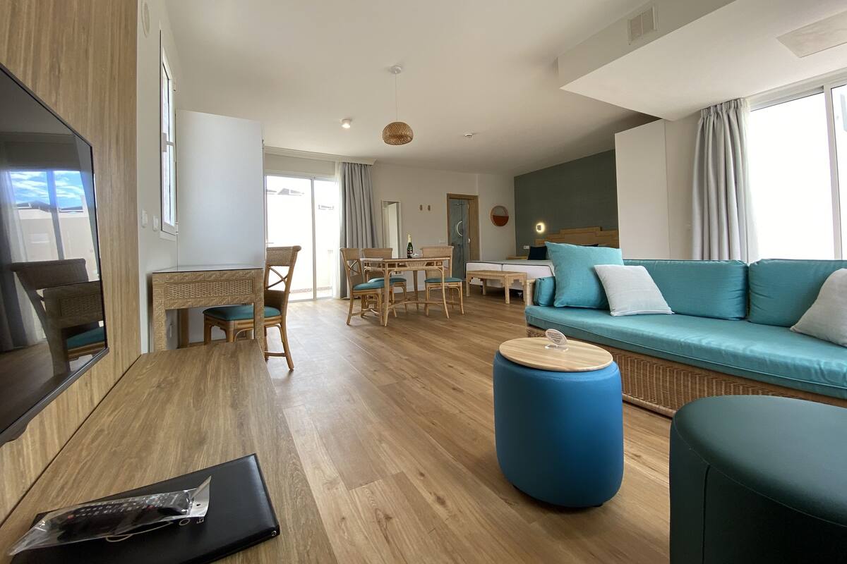 Un salon moderne avec un canapé, un pouf et un coin repas.