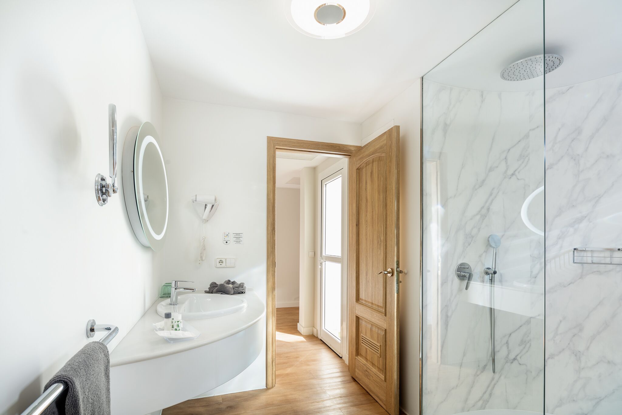 A modern bathroom with a white sink, mirror, and shower.
