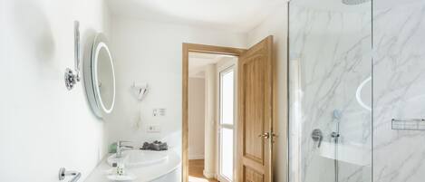 A modern bathroom with a white sink, mirror, and shower.