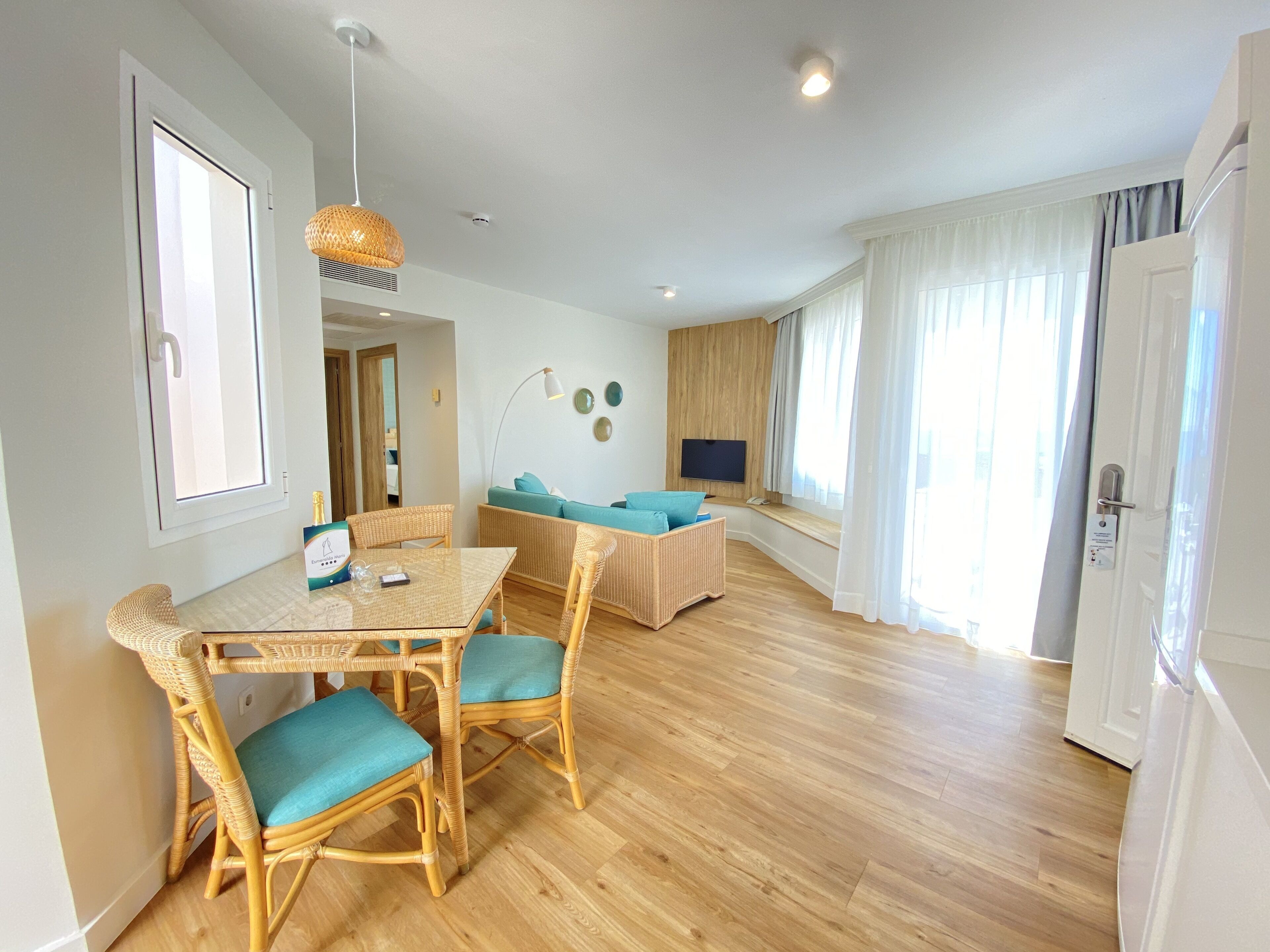 Un salon moderne comprenant un coin repas, un parquet et une grande fenêtre agrémentée de rideaux.