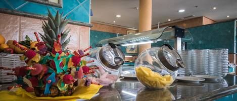 A breakfast bar with a variety of fruits and a coffee machine.