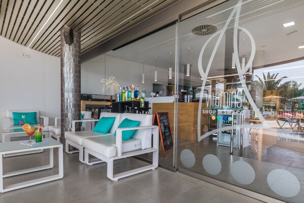 A modern lounge area with white sofas and a glass wall overlooking a bar area. - Hotel Esmeralda Maris by LIVVO (Pajara)