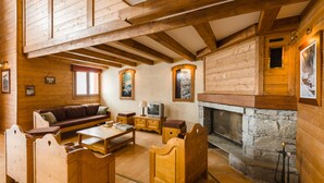 Ein Holzblockhaus-Interieur mit Kamin aus Stein, Holzmöbeln und einem Fernseher.