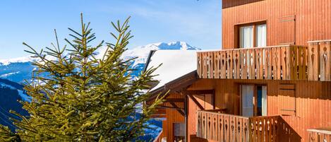 Un chalet en bois doté d’un balcon donnant sur une montagne enneigée.