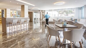 A modern hotel lobby with a bar area, seating arrangements, and large windows. - Grupotel Farrutx (Santa Margalida)