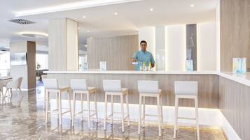A modern bar area with a counter, bar stools, and a person serving.