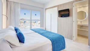 A modern hotel room with a large bed, a TV mounted on the wall, and a view of the city through the window. - Grupotel Farrutx (Santa Margalida)