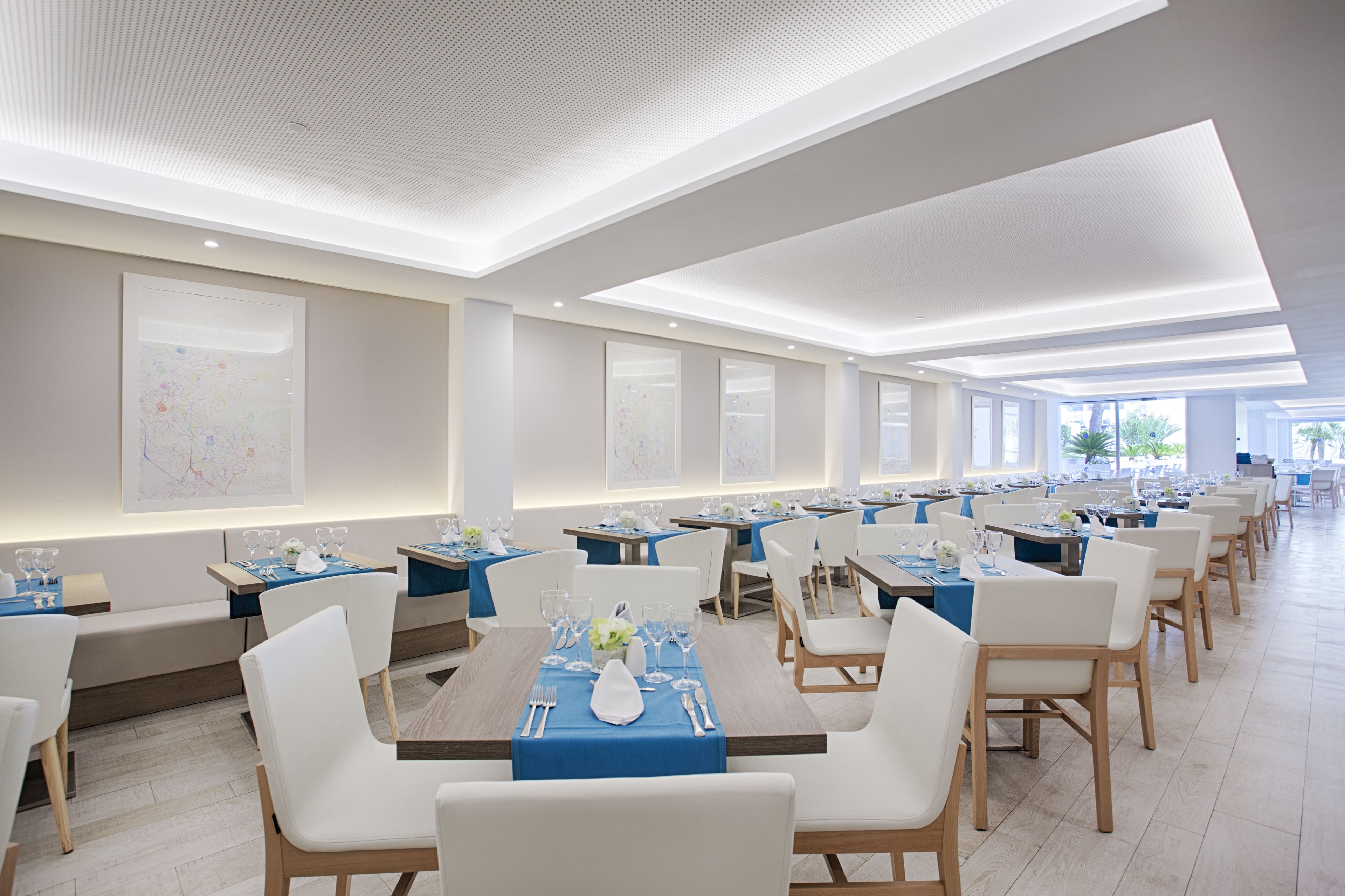 A modern dining area with long tables, white chairs, and blue tablecloths.