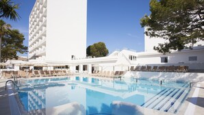 A swimming pool with lounge chairs and a white building with balconies. - Grupotel Farrutx (Santa Margalida)