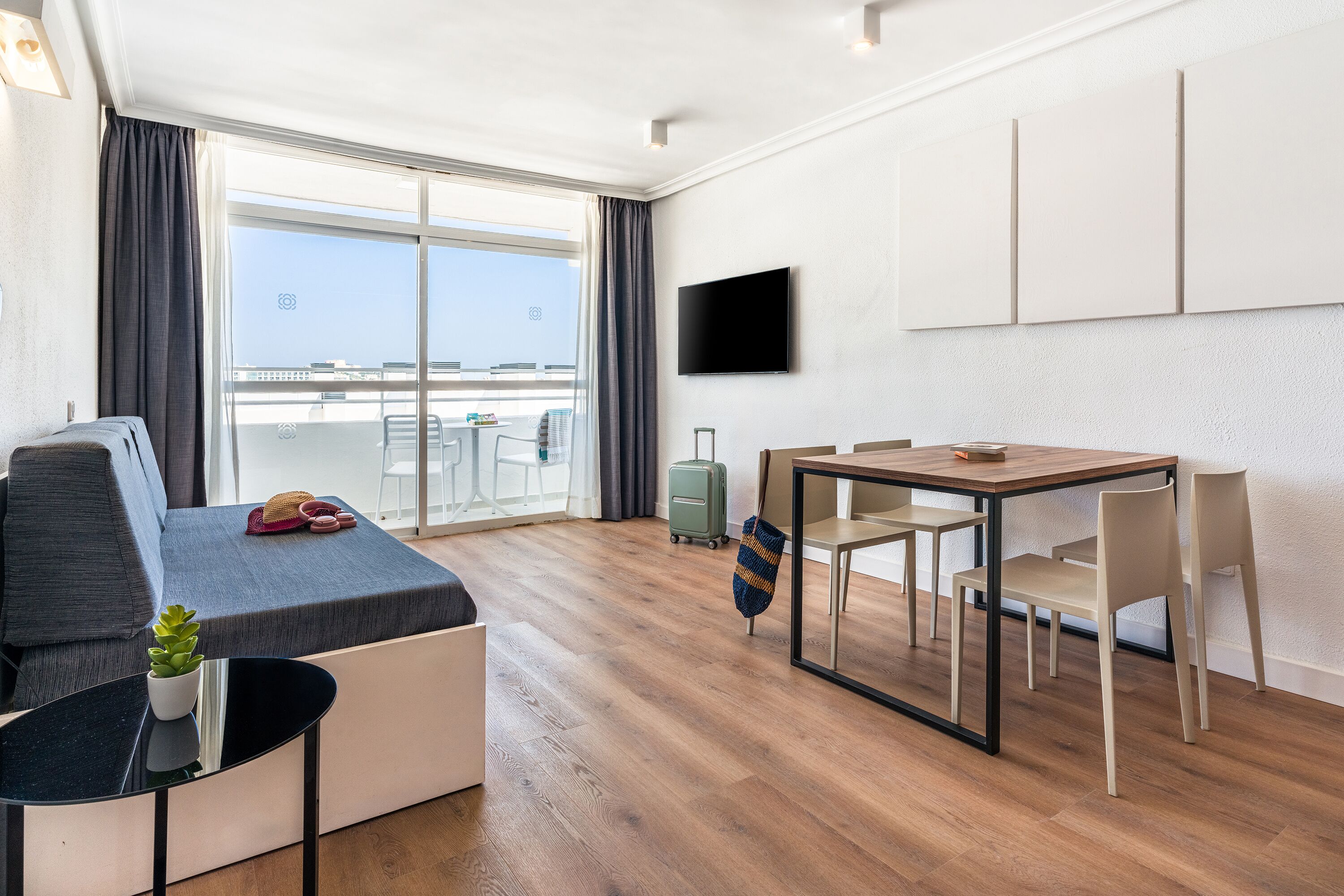 Et moderne hotelværelse med sofa, spisebord, TV og udsigt over byen.