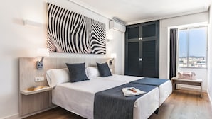 Een moderne hotelkamer met een groot bed, wanddecoratie met een zebraprint, een raam met uitzicht en een houten vloer.