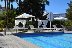 Una piscina al aire libre, sillones reclinables de piscina