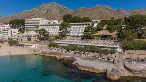 Et kysthotel med flere etager, en strand og klart, blåt vand.