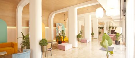 A modern lobby with a curved seating area, potted plants, and a wooden ceiling.