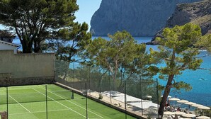 En tennisbane med udsigt til havet og klipper.