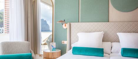 A hotel room with a bed, a chair, a round table, and a view of the outside.