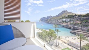 En balkon med udsigt over en kystby, strand og både.