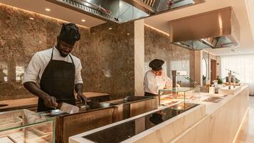 A modern kitchen with marble countertops, stainless steel appliances, and a glass display case.