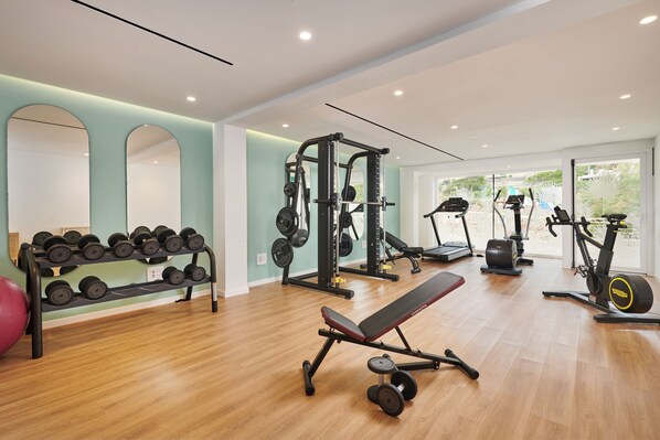 A modern gym with weightlifting equipment, treadmills, and a bench.