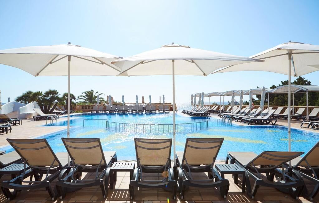 Un área de piscina con sillones de descanso y sombrillas.