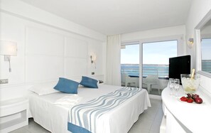 A hotel room with a bed, a desk with a bottle of champagne and glasses, and a view of the sea. - Insotel Hotel Formentera Playa (Formentera)