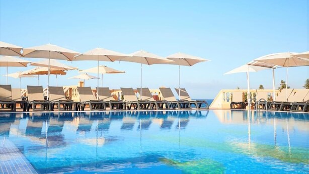 A poolside area with lounge chairs and umbrellas, reflecting in the water. - Insotel Hotel Formentera Playa (Formentera)