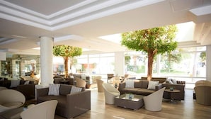 A spacious lobby with modern furniture, large windows, and indoor trees. - Insotel Hotel Formentera Playa (Formentera)