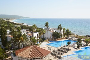 Un resort con piscina, palmeras y vista al océano.