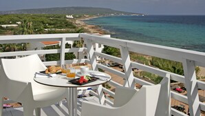 A balcony with a table set for breakfast, overlooking a coastal landscape with buildings and a beach. - Insotel Hotel Formentera Playa (Formentera)