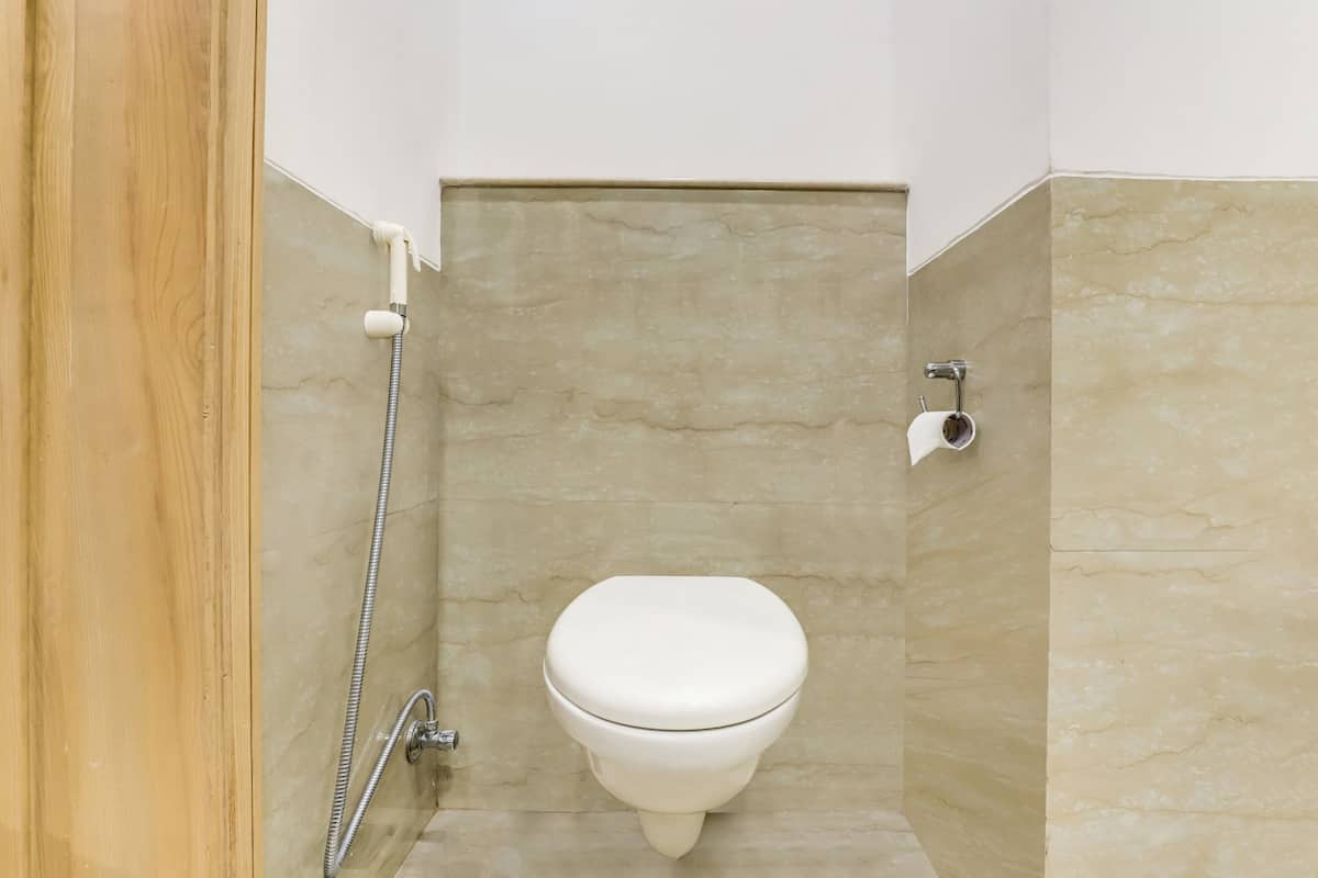 A bathroom with a toilet, a shower, and a toilet paper holder.