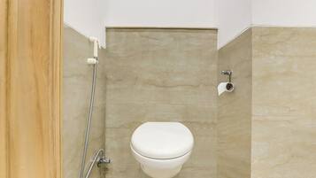 A bathroom with a toilet, a shower, and a toilet paper holder.