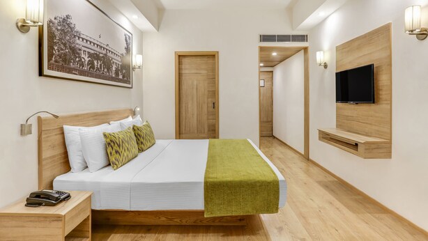 A modern hotel room with a wooden bed, a mounted TV, and a framed picture on the wall. - Lemon Tree Premier City Center Gurugram (Gurugram)