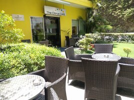 Un área de estar al aire libre con mobiliario de mimbre y un cartel que anuncia The Citrus Café.