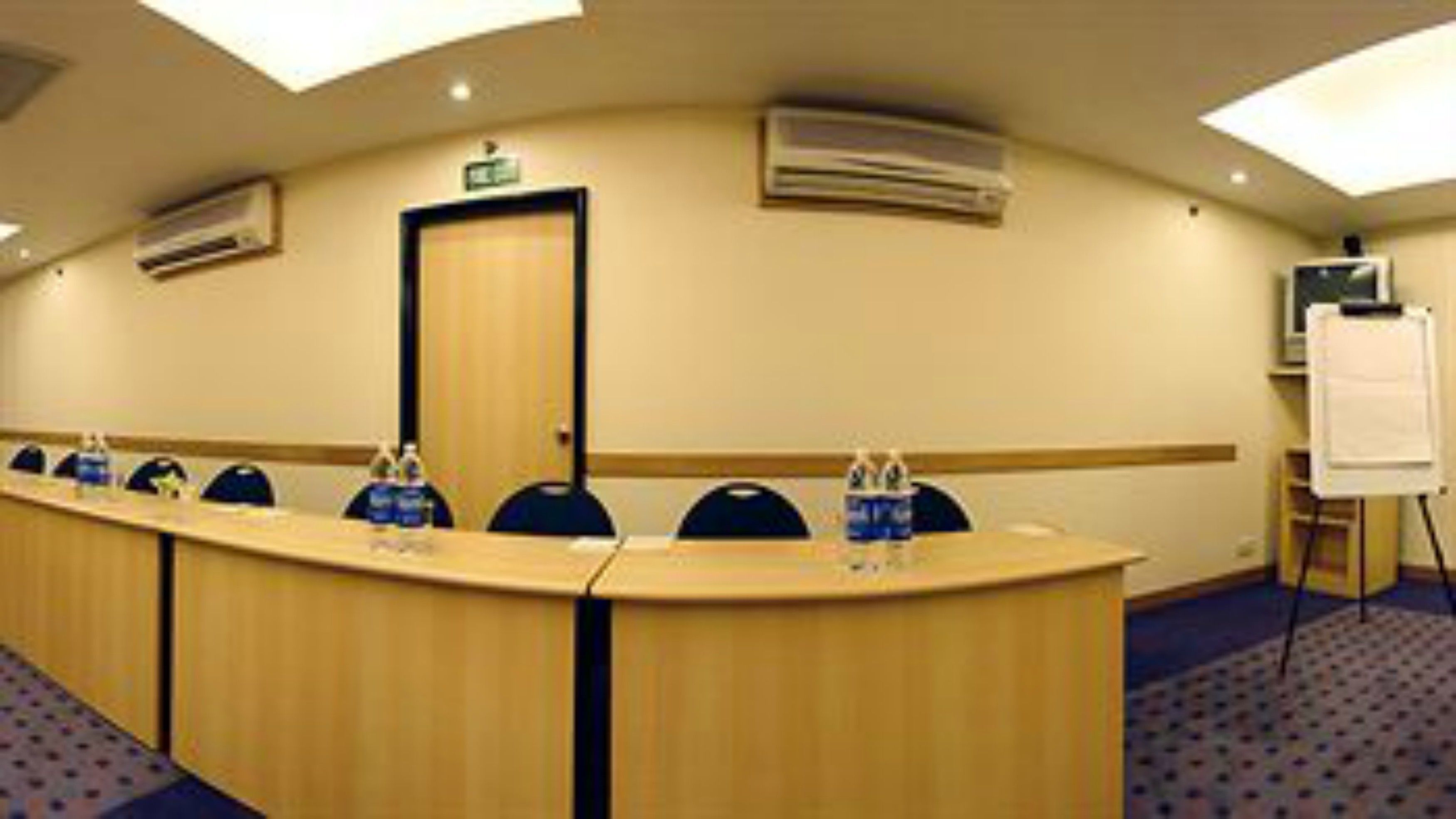 A conference room with a long table, chairs, and a whiteboard.