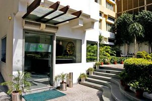 Un edificio moderno con entrada de vidrio, escalones exteriores y plantas en macetas.
