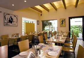 Un restaurante con mesas dispuestas para comer, sillas y obras de arte en las paredes.