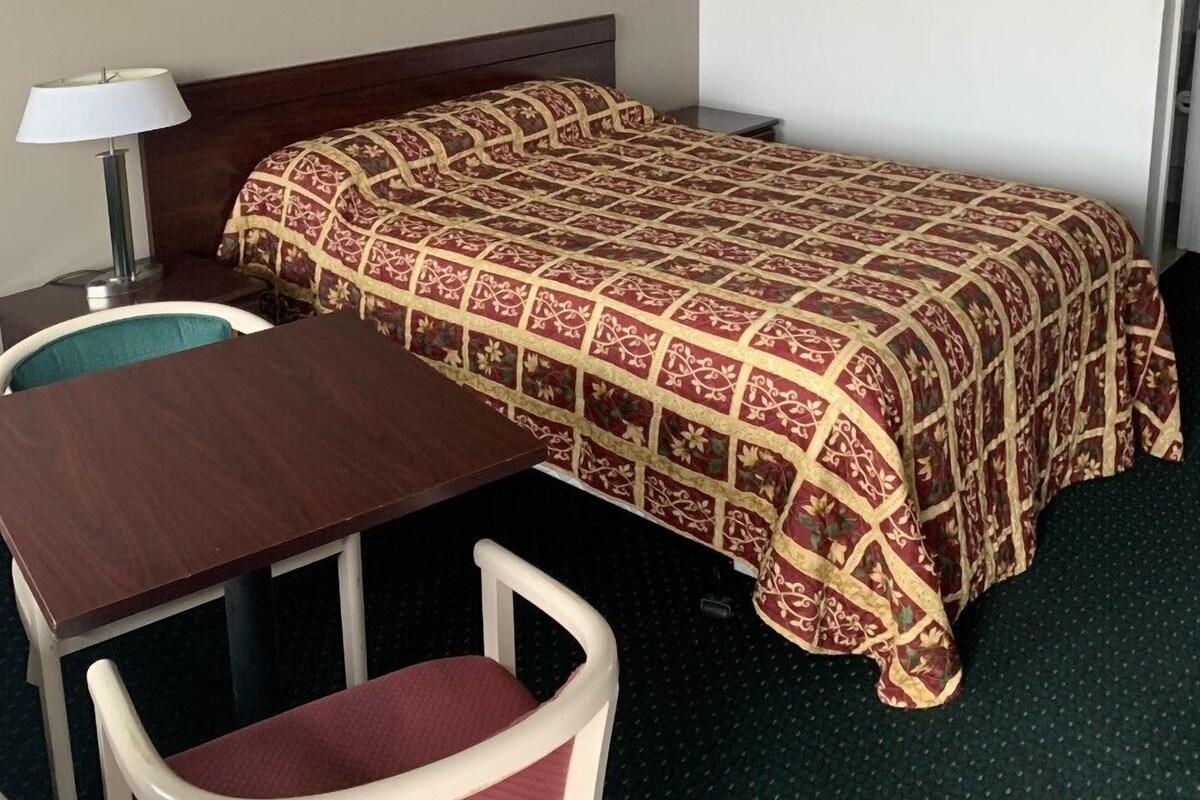A hotel room with a bed, a desk, and a chair.