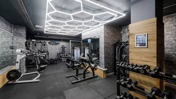 Een sportschool met diverse fitnessapparaten, waaronder krachttoestellen en gewichten.
