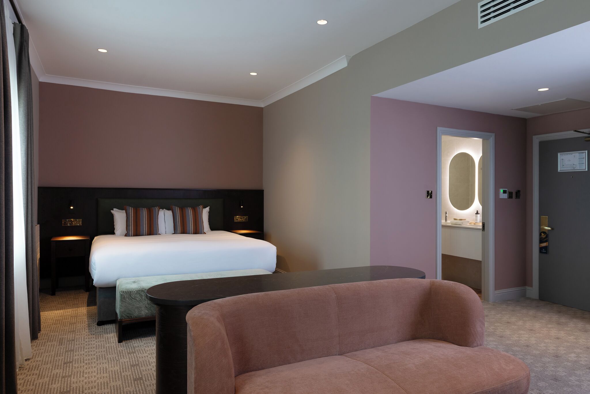 Une chambre d’hôtel avec un lit, une table de chevet, une table ronde et un canapé.