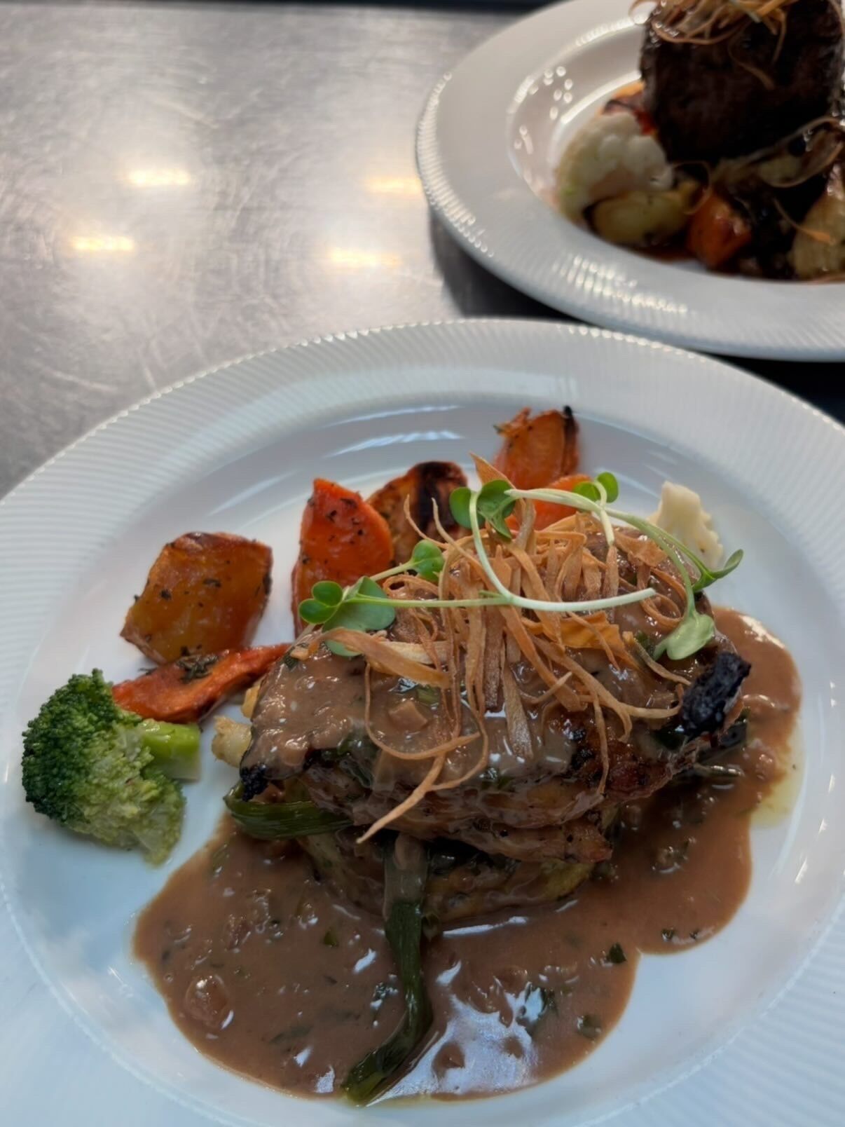 Een bord eten met een vleesgerecht, groenten en saus.